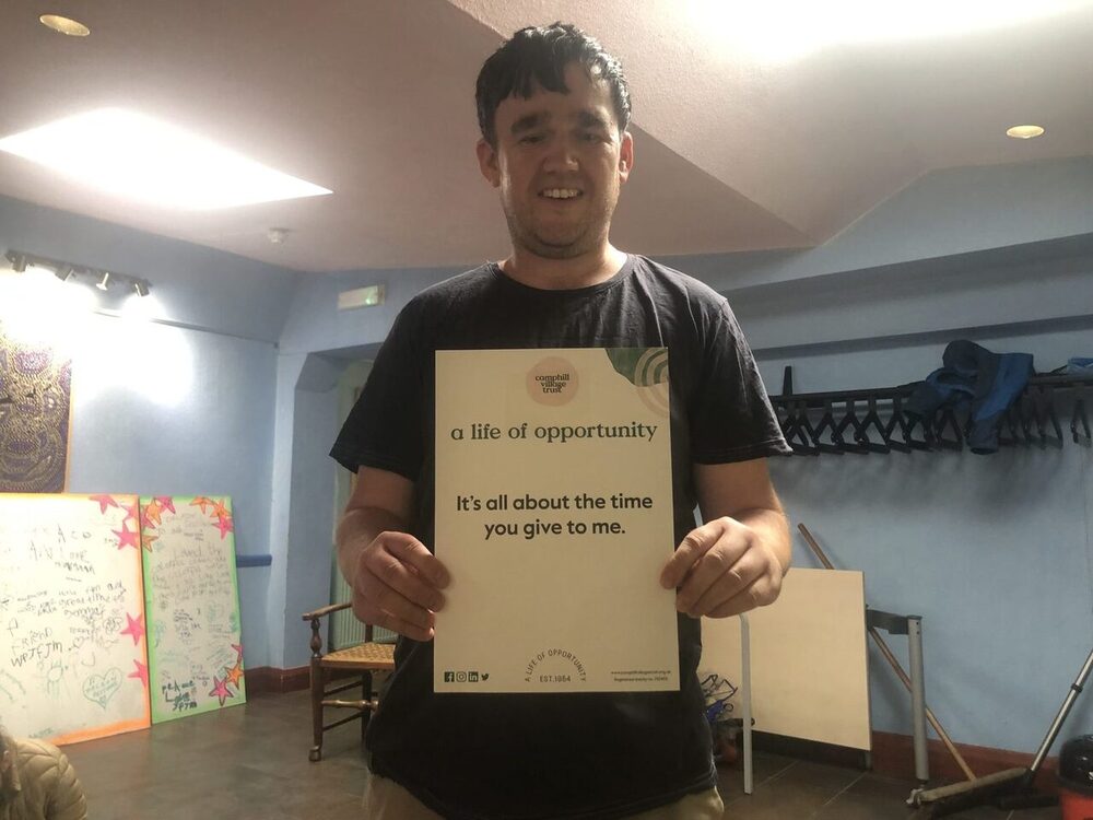 A person we support smiling and holding an i-statement card